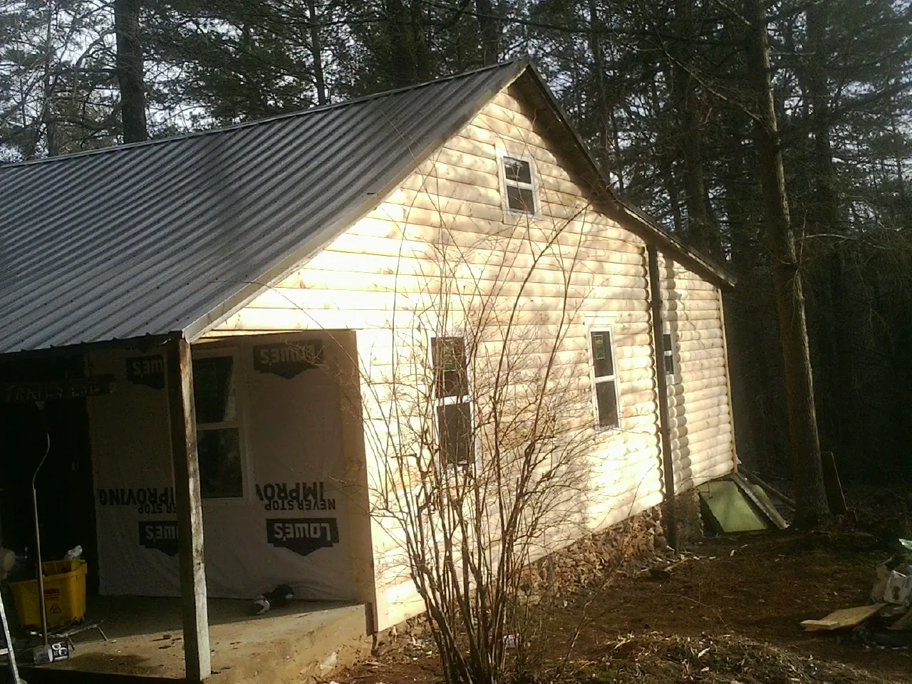 Log siding gable end under a dark metal roof edge in Canton